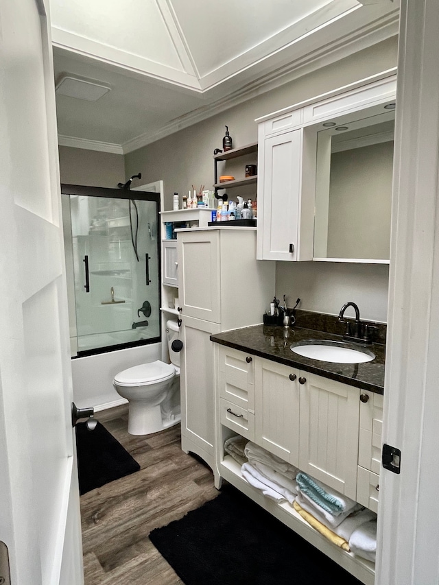 bathroom featuring crown molding, shower / bath combination with glass door, toilet, vanity, and wood finished floors