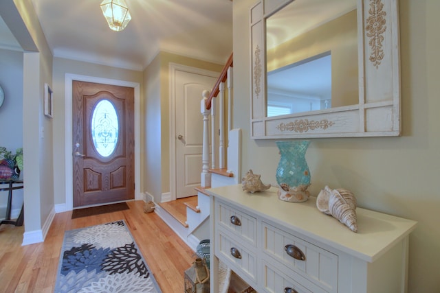 foyer entrance featuring light wood-type flooring, baseboards, and stairway