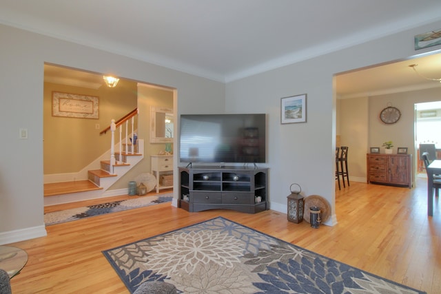 living area featuring ornamental molding, stairway, wood finished floors, and baseboards