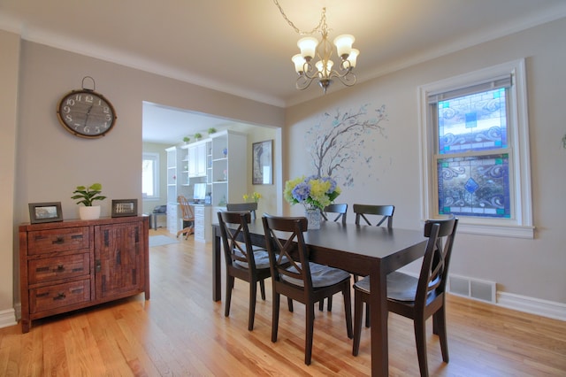 dining room featuring a chandelier, light wood-type flooring, visible vents, and baseboards