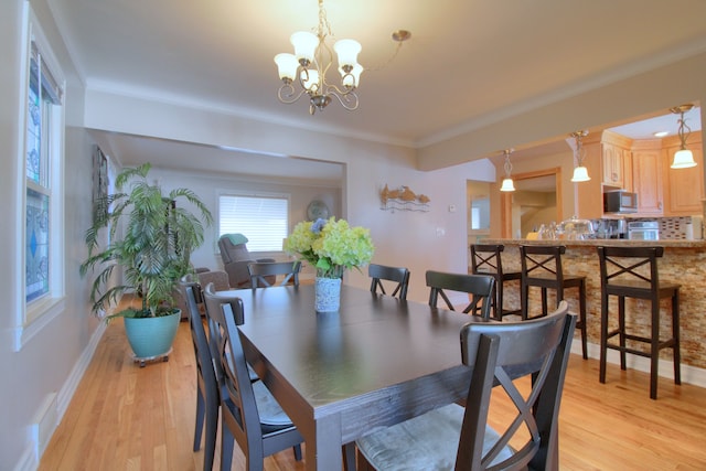 dining area featuring an inviting chandelier, light wood-style flooring, and baseboards