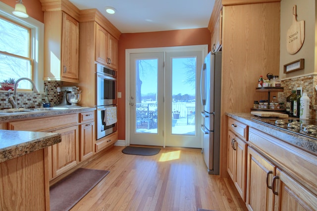 kitchen with light brown cabinets, a sink, light countertops, appliances with stainless steel finishes, and decorative light fixtures