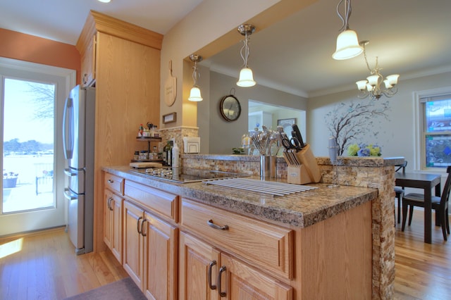 kitchen with plenty of natural light, freestanding refrigerator, light brown cabinets, and hanging light fixtures