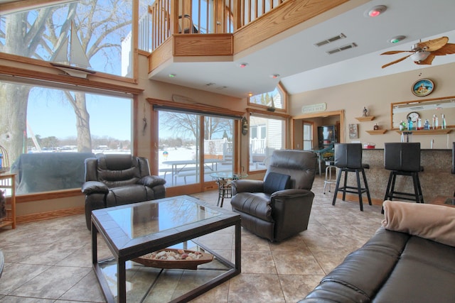 living room featuring light tile patterned floors, visible vents, a towering ceiling, and a ceiling fan