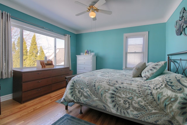 bedroom featuring light wood finished floors, baseboards, and a ceiling fan