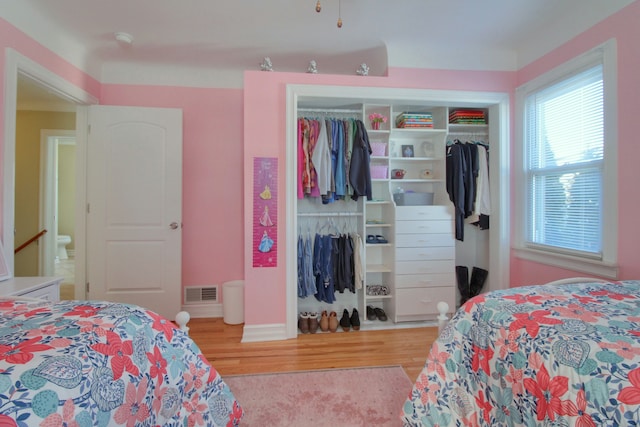 bedroom featuring light wood-type flooring, baseboards, visible vents, and a closet