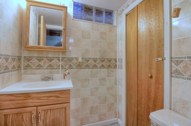 bathroom featuring tasteful backsplash, vanity, toilet, and tile walls