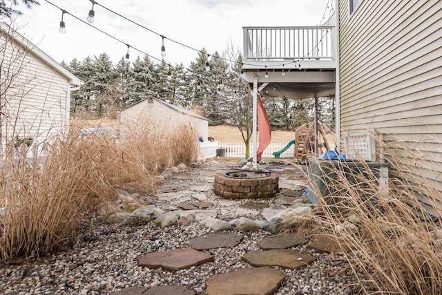 view of yard with a balcony, a fire pit, and fence