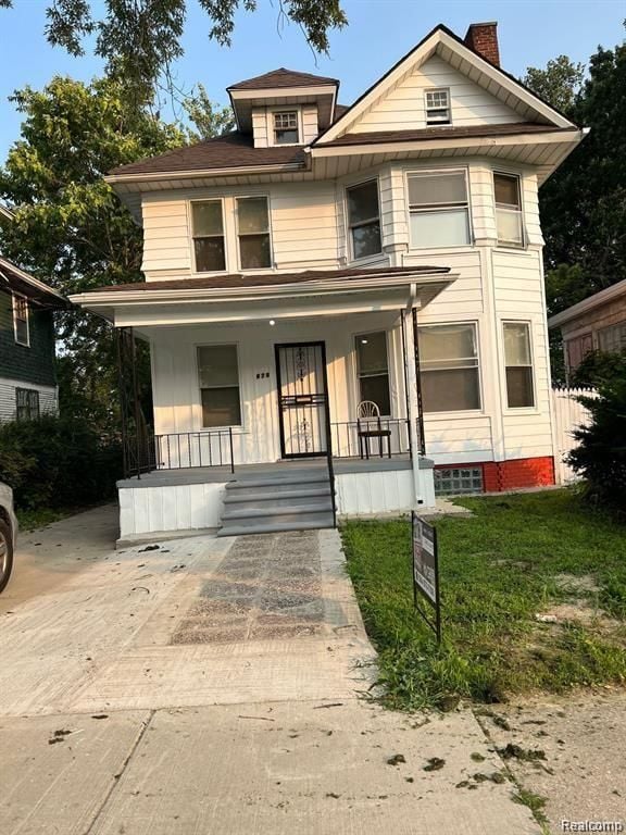 view of front of property featuring a porch, a chimney, and a front yard