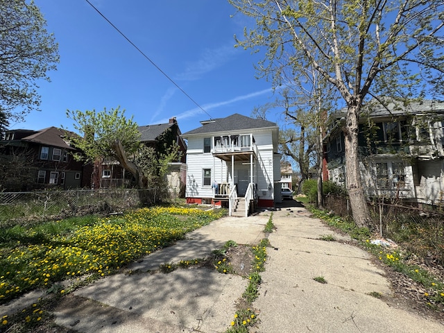 view of front of property featuring a porch, fence, a balcony, and concrete driveway