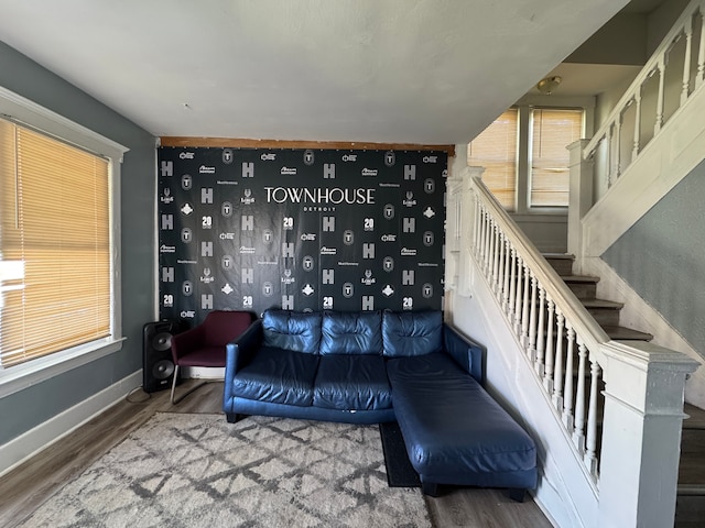 living room featuring stairs, baseboards, a healthy amount of sunlight, and wood finished floors