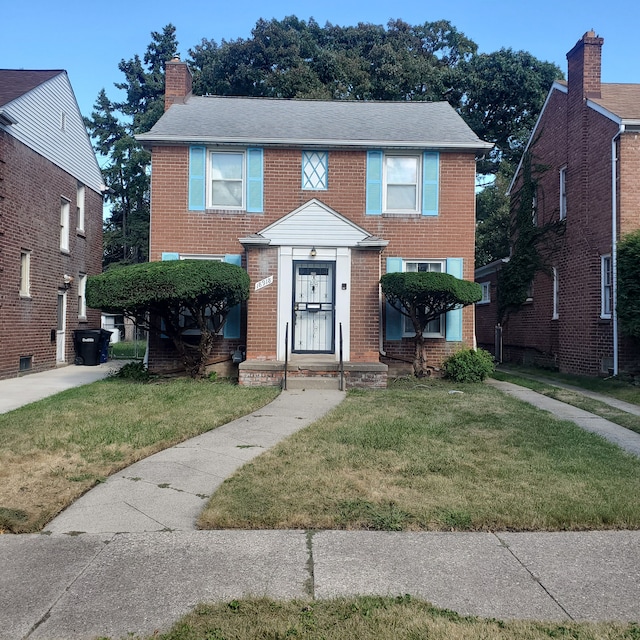 view of front of house with a front yard, brick siding, and a chimney