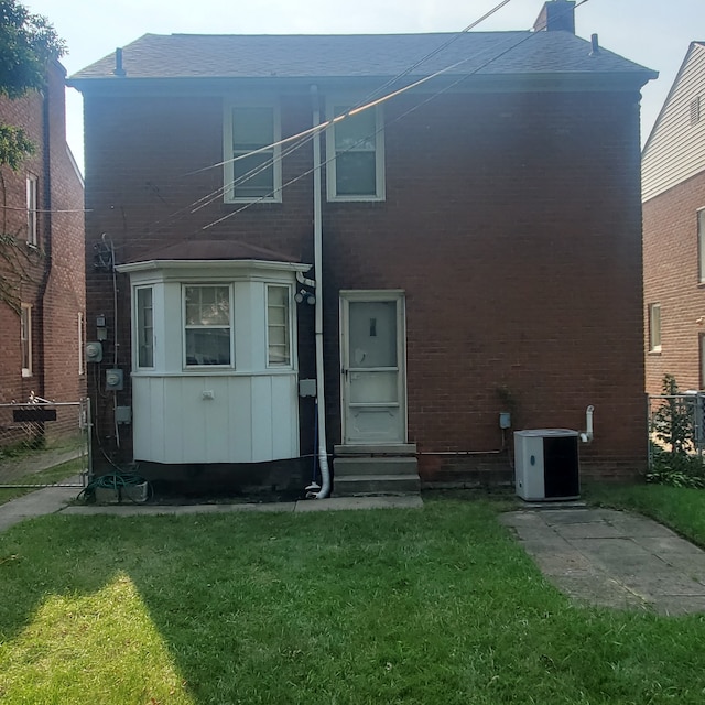 view of front facade with entry steps, a front lawn, fence, and central air condition unit