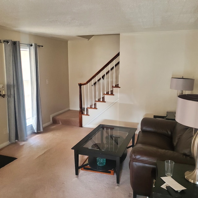 living room featuring stairs, baseboards, a textured ceiling, and light colored carpet