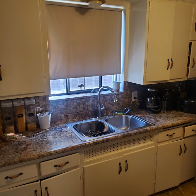 kitchen with backsplash, dark countertops, a sink, and a wealth of natural light