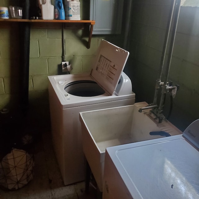 laundry area featuring concrete block wall, laundry area, and separate washer and dryer