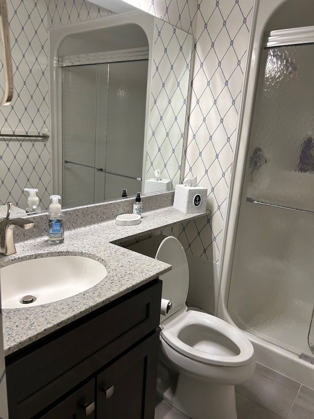 bathroom featuring double vanity, a stall shower, a sink, and toilet