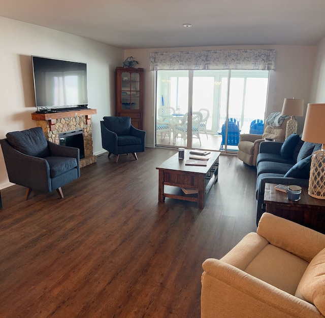 living area featuring a stone fireplace, dark wood-style flooring, and baseboards