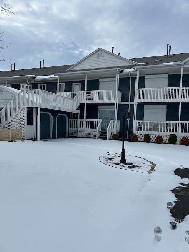 snow covered property with a garage and stairway