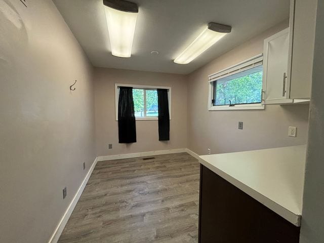 unfurnished room featuring light wood finished floors, plenty of natural light, and baseboards