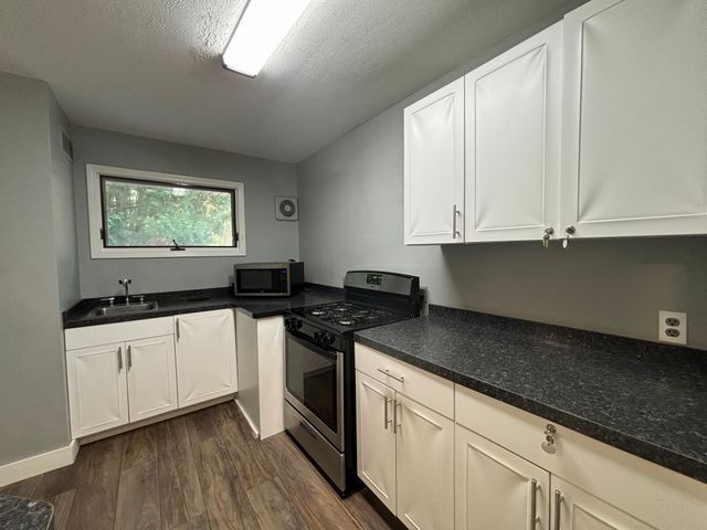 kitchen with dark countertops, white cabinetry, appliances with stainless steel finishes, and a sink