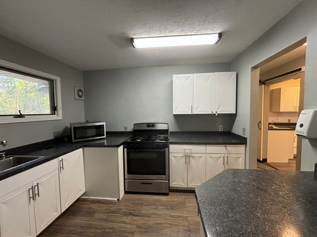 kitchen with appliances with stainless steel finishes, dark countertops, and white cabinetry