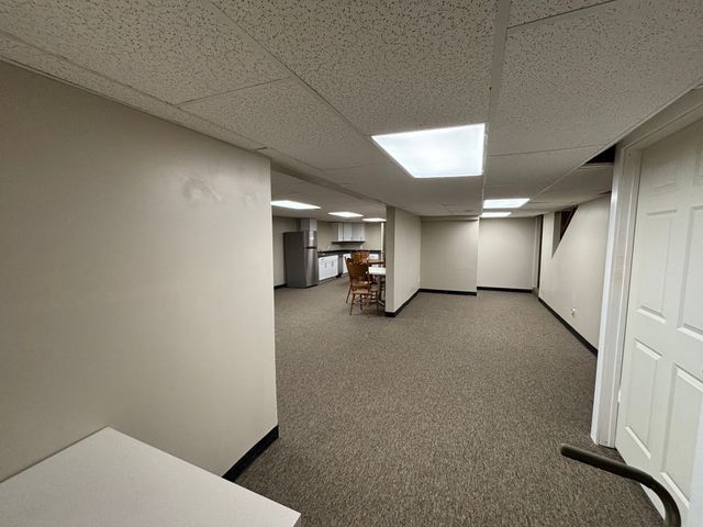 finished below grade area with freestanding refrigerator, a drop ceiling, and baseboards