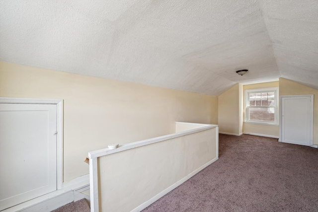 additional living space with lofted ceiling, carpet flooring, a textured ceiling, and baseboards