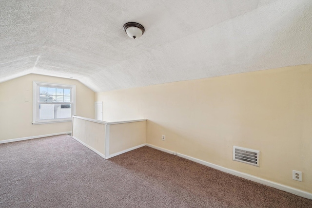 bonus room featuring baseboards, visible vents, vaulted ceiling, a textured ceiling, and carpet flooring