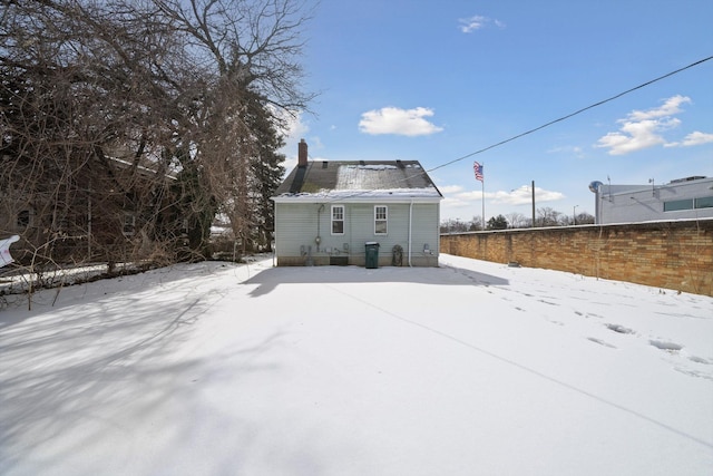 snow covered rear of property with a chimney