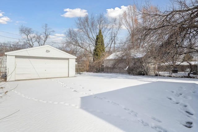 yard layered in snow featuring a detached garage and an outdoor structure