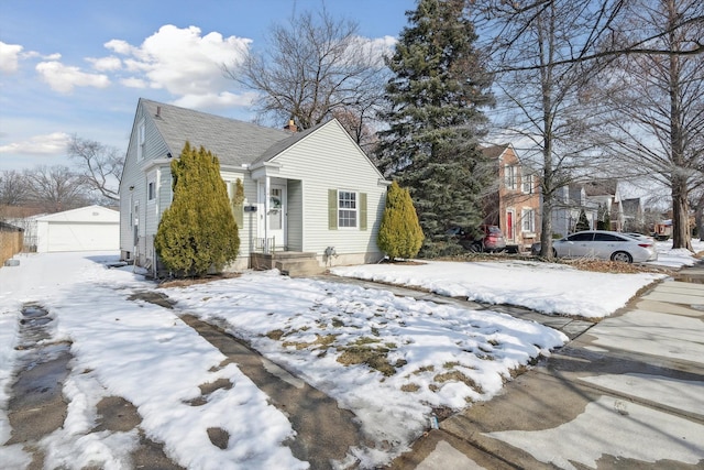 view of front of property featuring a garage, a shingled roof, and an outbuilding