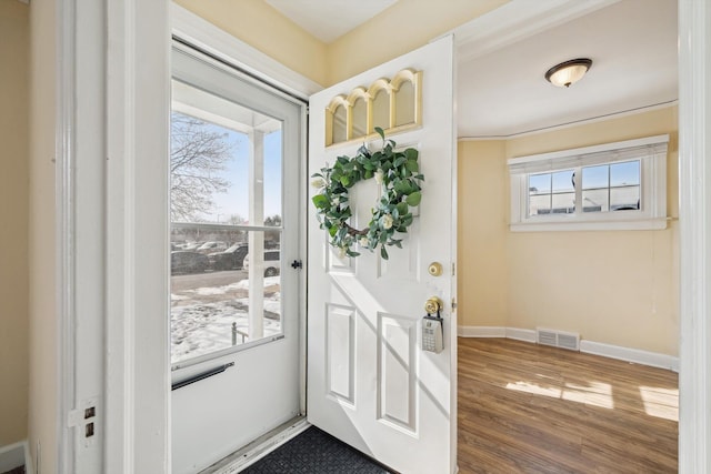 doorway to outside featuring visible vents, baseboards, and wood finished floors