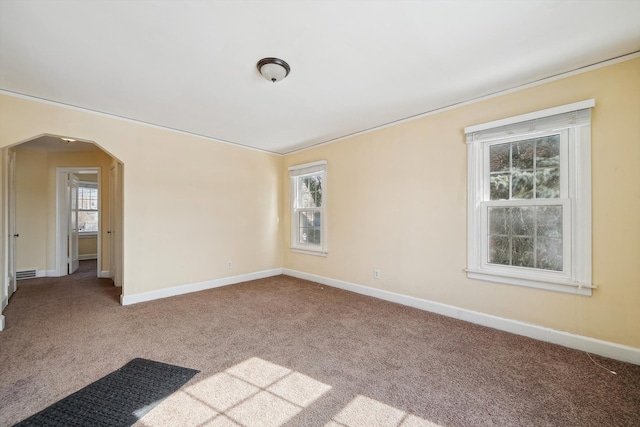 unfurnished room featuring arched walkways, light carpet, and baseboards