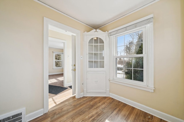 unfurnished dining area with a wealth of natural light, visible vents, baseboards, and wood finished floors