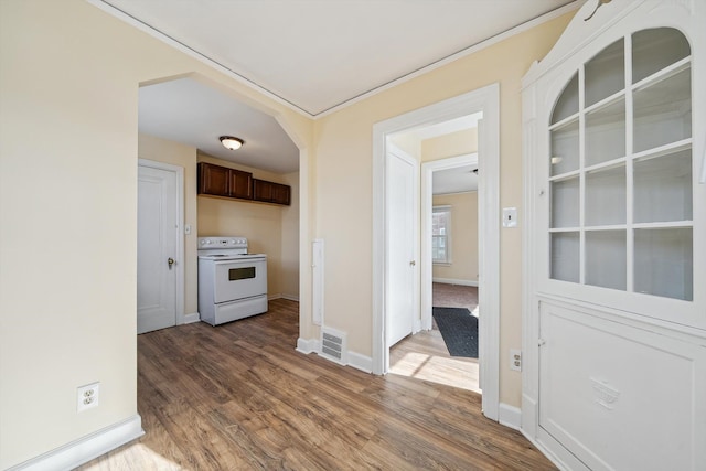 interior space featuring white range with electric stovetop, baseboards, visible vents, wood finished floors, and dark brown cabinets