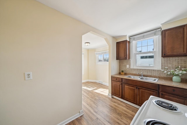 kitchen featuring light wood-type flooring, backsplash, light countertops, and a sink