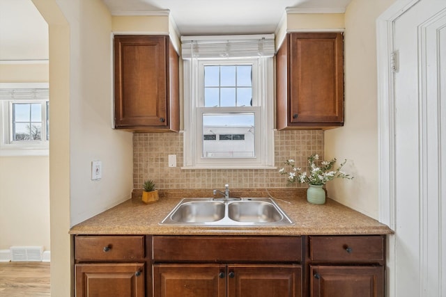 kitchen featuring visible vents, backsplash, a sink, and light countertops