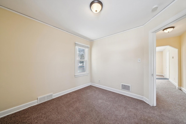 unfurnished room with carpet, visible vents, arched walkways, and baseboards