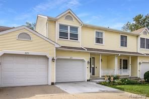 view of property with covered porch, driveway, and a garage