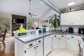 kitchen with dishwasher, a peninsula, a sink, and white cabinetry