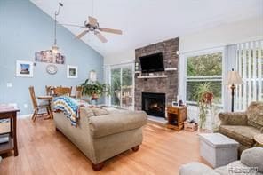 living room with a ceiling fan, a fireplace, a wealth of natural light, and light wood-style floors