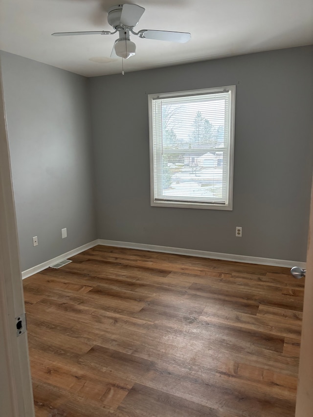 unfurnished room with a ceiling fan, visible vents, baseboards, and wood finished floors