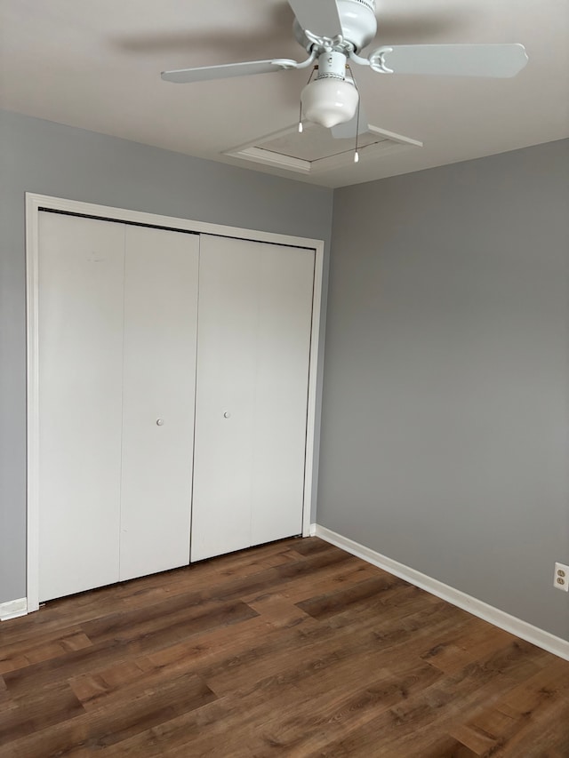 unfurnished bedroom featuring a ceiling fan, baseboards, dark wood-style flooring, and a closet