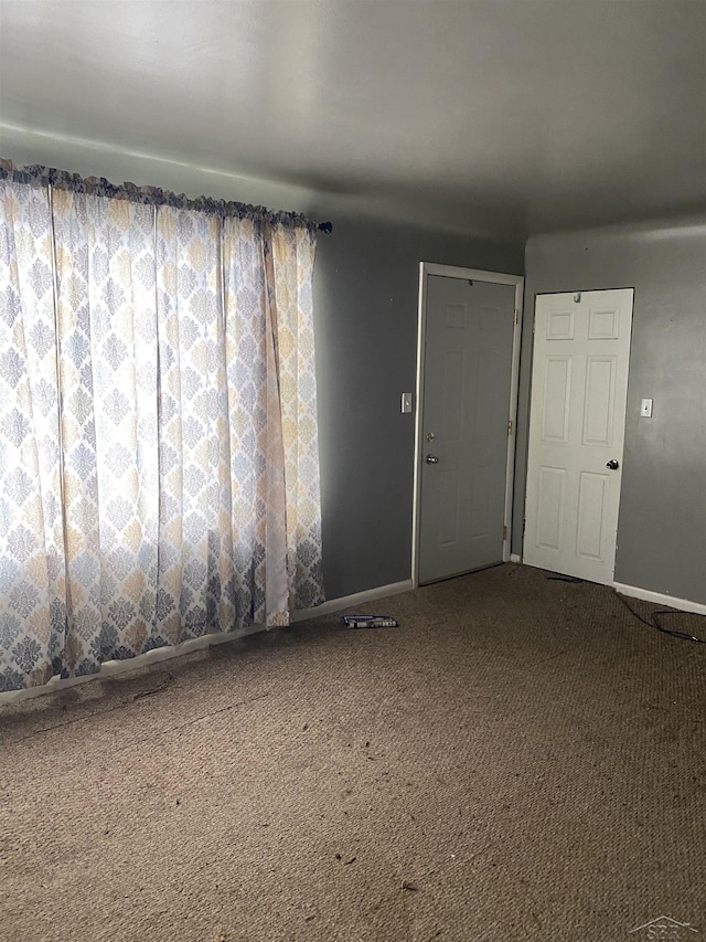 carpeted spare room featuring baseboards