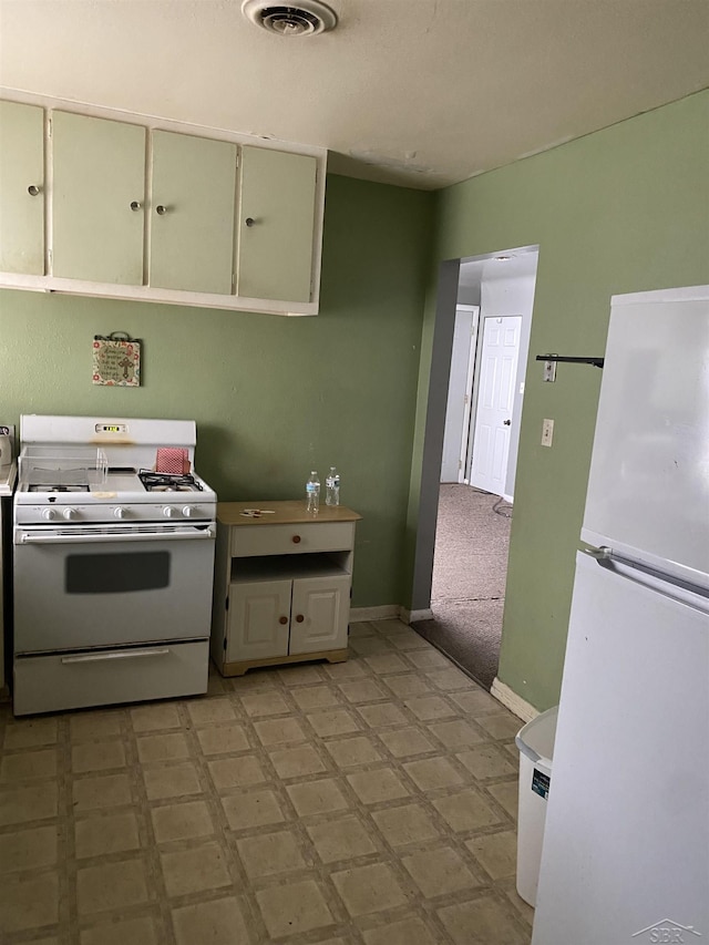 kitchen with light floors, white appliances, visible vents, and baseboards