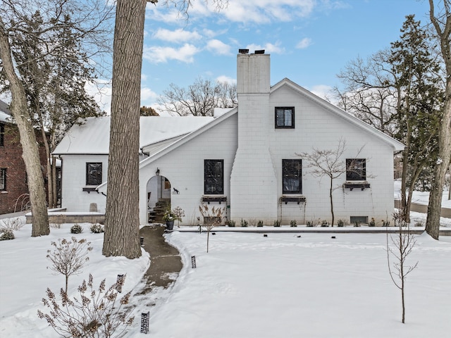 snow covered rear of property with a chimney