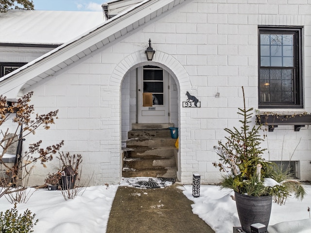 snow covered property entrance with brick siding