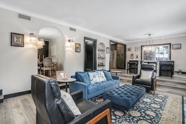 living area featuring light wood-type flooring, an inviting chandelier, arched walkways, and crown molding