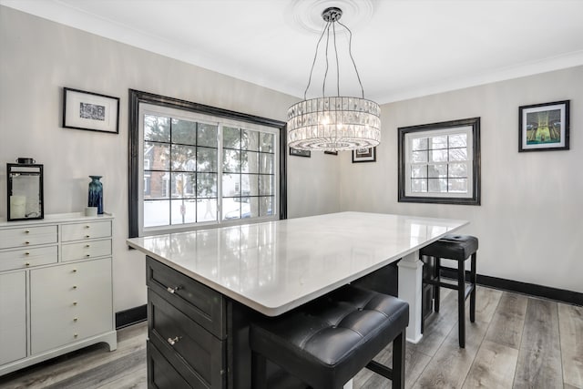 kitchen with a breakfast bar, light countertops, hanging light fixtures, a kitchen island, and dark cabinetry